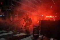 Firefighters put out a dumpster fire as protesters and police gather at Lafayette Park near the ...