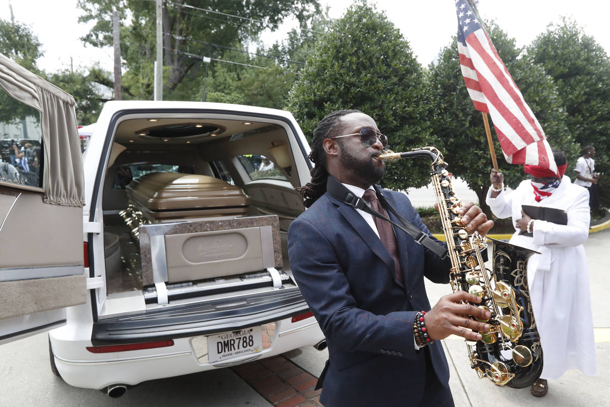 A musician plays music near the hearse carying the casket of Rayshard Brooks, Tuesday, June 23, ...