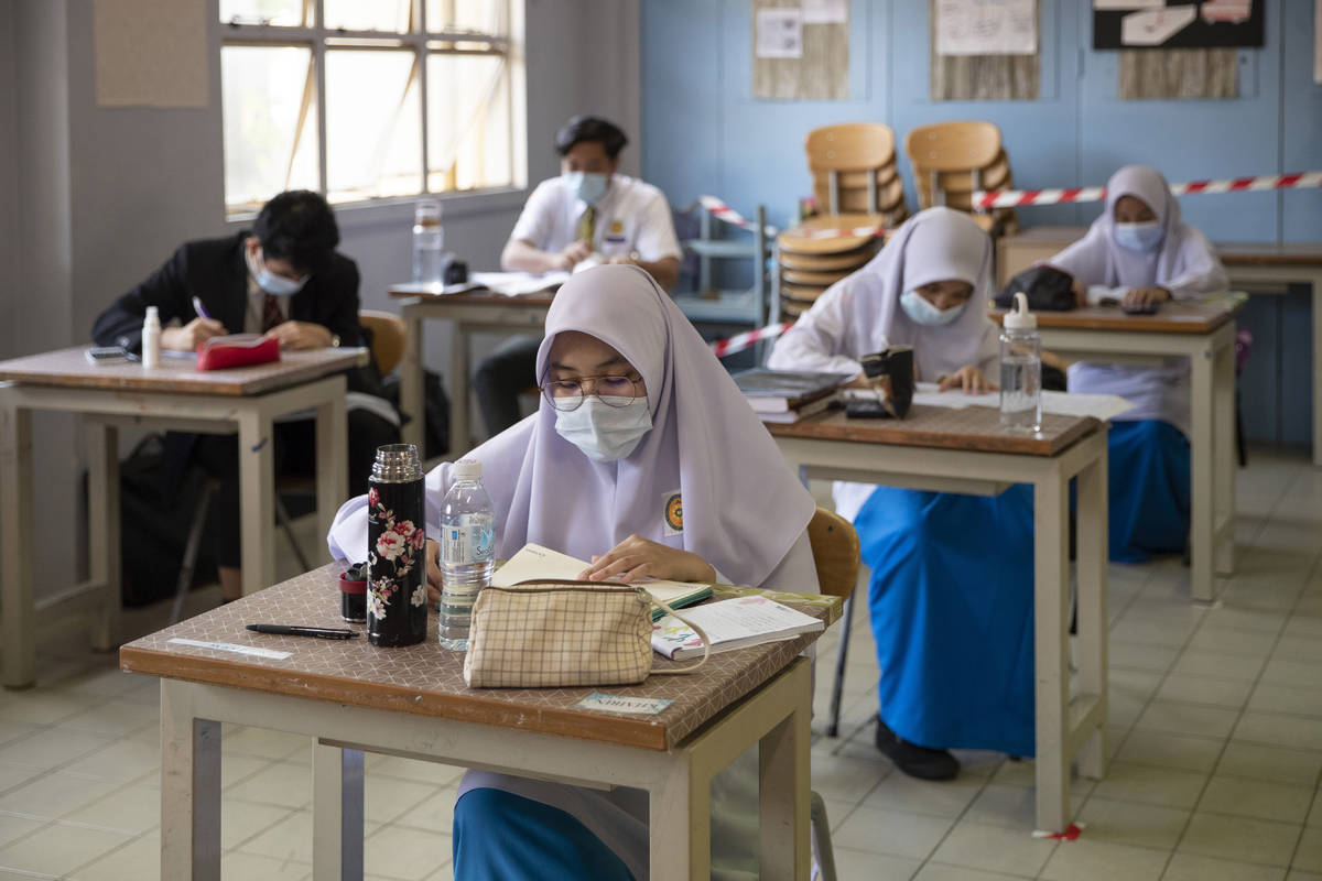 Students wearing face masks and maintaining social distancing at a classroom during the first d ...