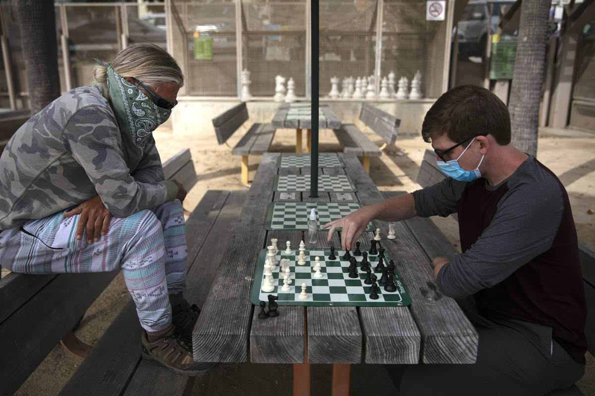Wearing face coverings, John Williams, right, and Jeff Lee play chess Tuesday, June 23, 2020, i ...