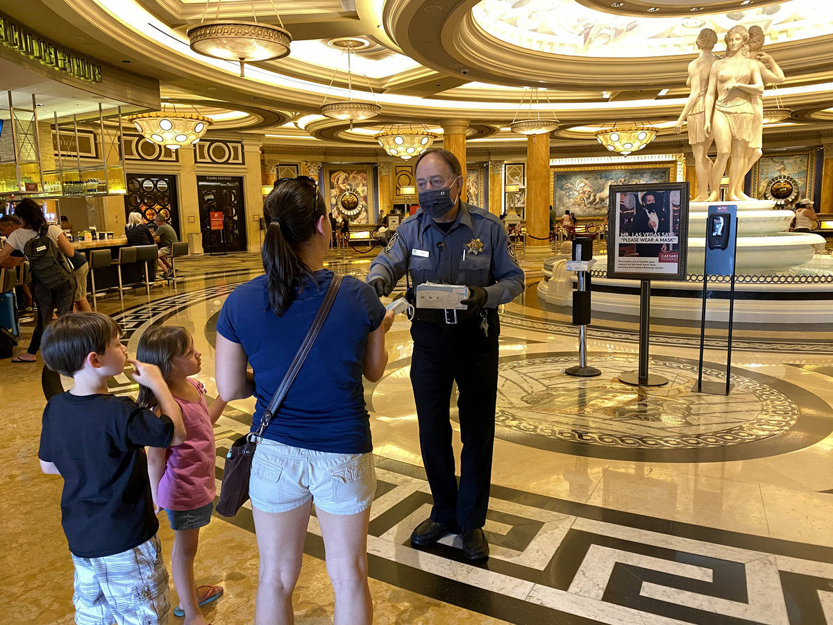 A security guard hands out face masks at Caesars on the Strip in Las Vegas Wednesday, June 24, ...