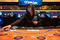 A Blackjack dealer wears a mask while she deals a game at Palace Station as casinos have reopen ...
