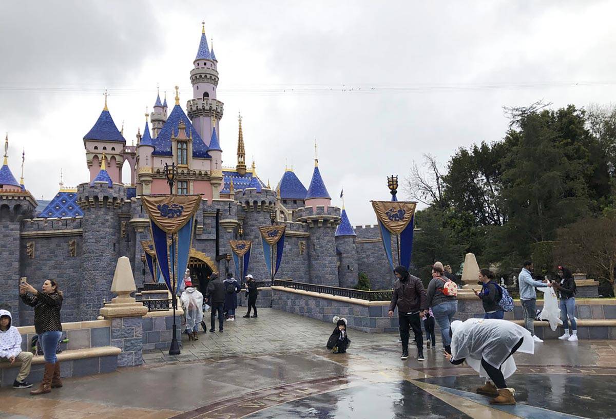 In this March 13, 2020, file photo, visitors take photos at Disneyland in Anaheim, Calif. Disne ...