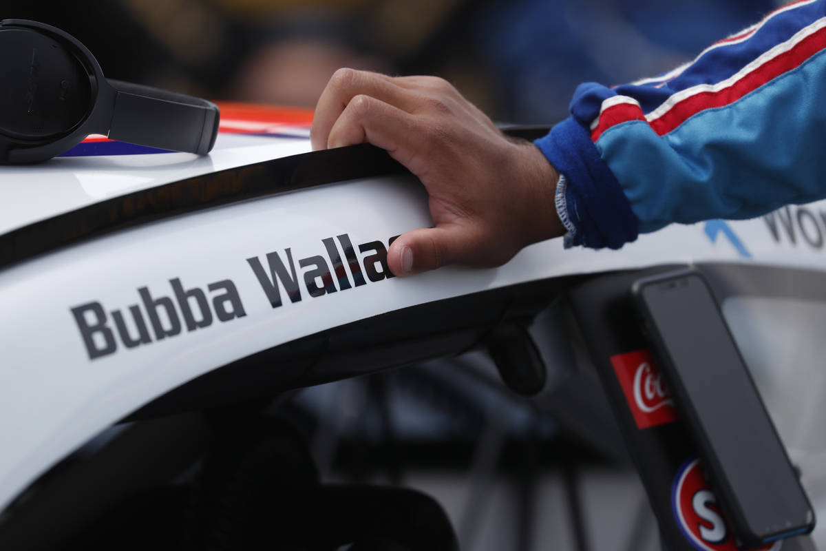 Driver Bubba Wallace leans on his car in the pits of the Talladega Superspeedway prior to the s ...