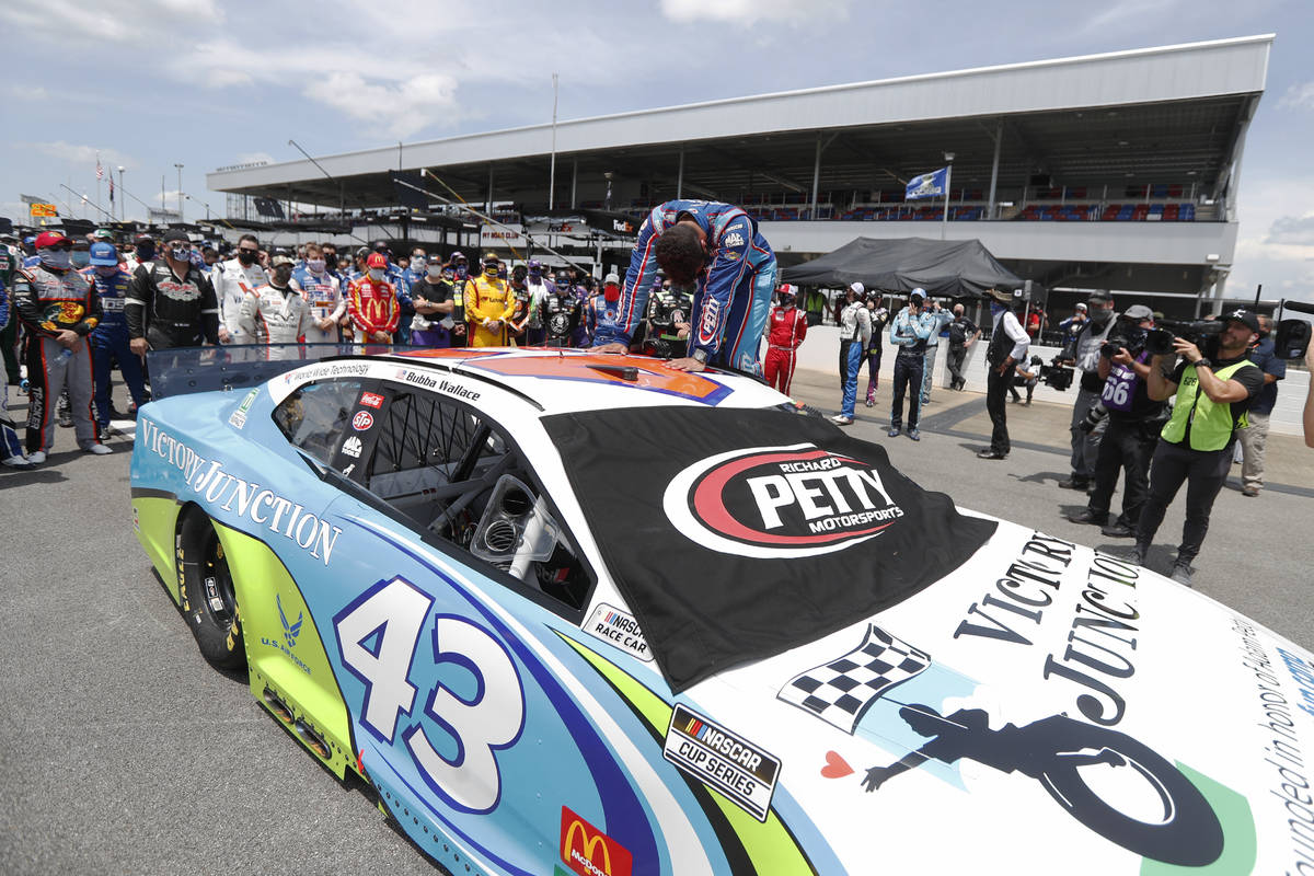 Driver Bubba Wallace, front, is overcome with emotion as he arrives at his car in the pits of t ...
