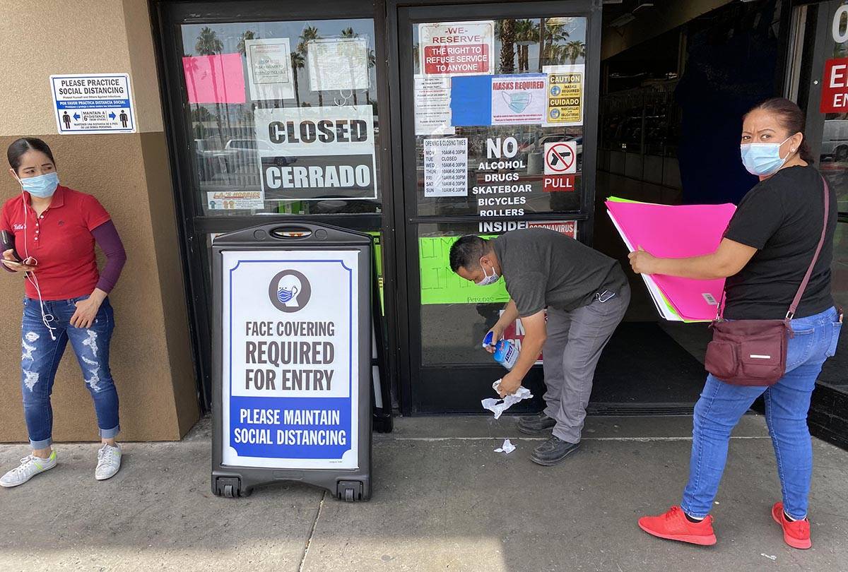 Eusebio Hernandez sanitizes doors as vendors arrive prior to opening at Bonanza Swap meet on Ea ...