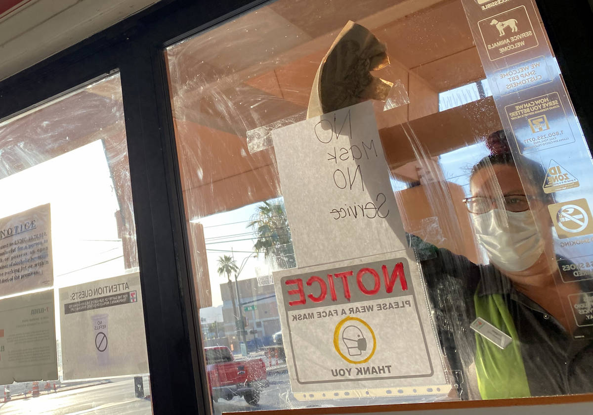 A clerk washes a window with a "No Mask No Service" sign at 7-11 on Las Vegas Bouleva ...