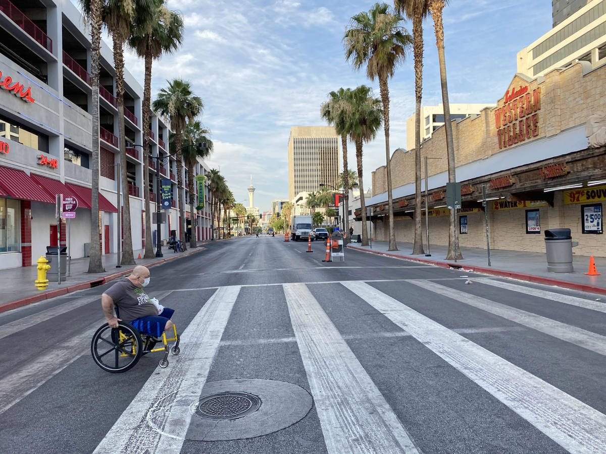 Paul Dodson of Las Vegas dons a face mask while crossing 4th Street at Fremont Street in downto ...