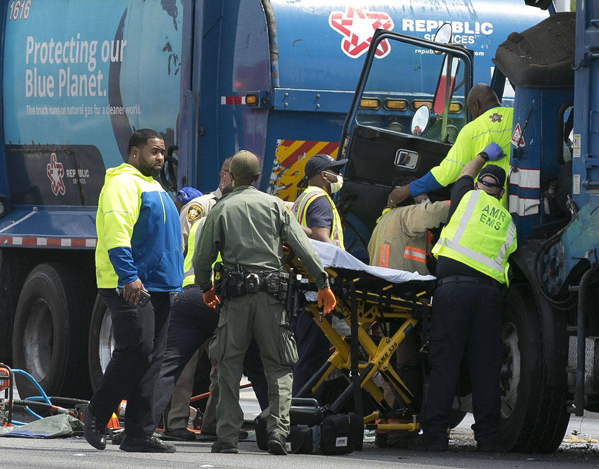 Emergency medical service workers remove a driver from his truck after a crash involving two ga ...
