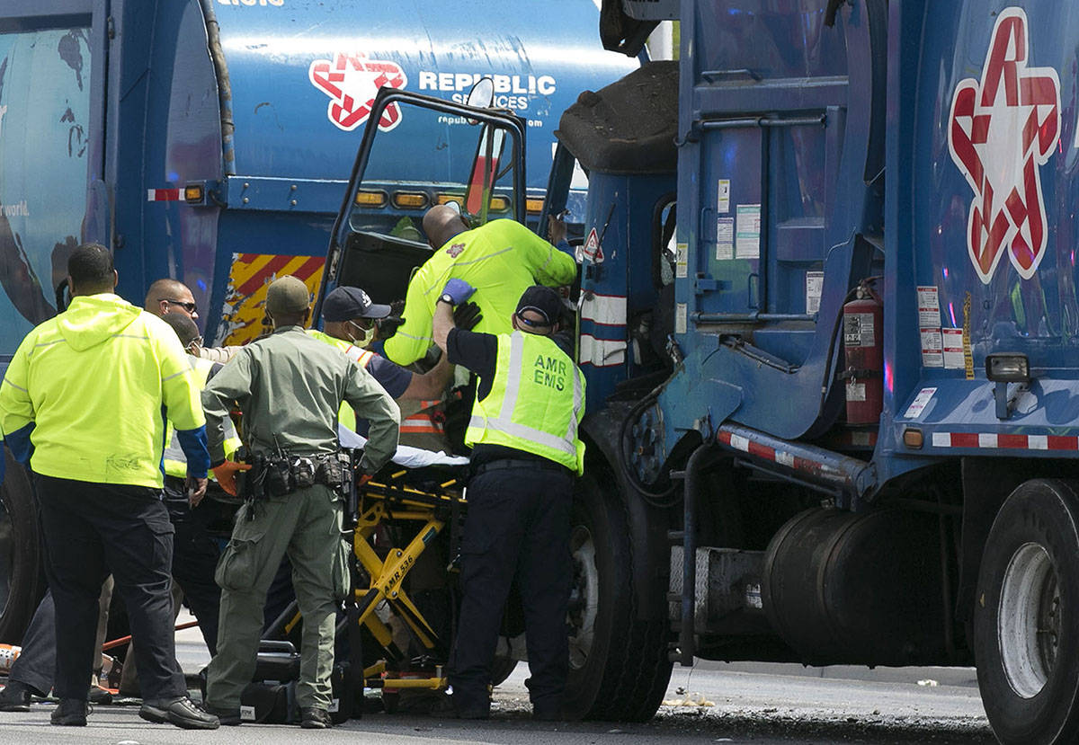 Emergency medical service workers remove a driver from his truck after a crash involving two ga ...
