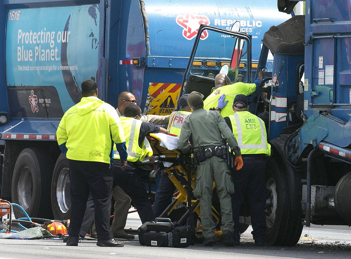 Emergency medical service workers remove a driver from his truck after a crash involving two ga ...