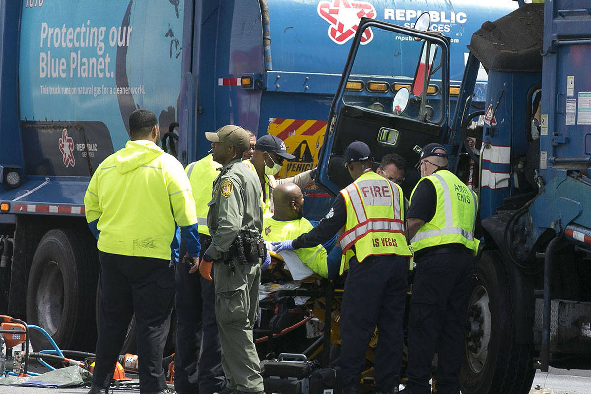 Emergency medical service workers remove a driver from his truck after a crash involving two ga ...