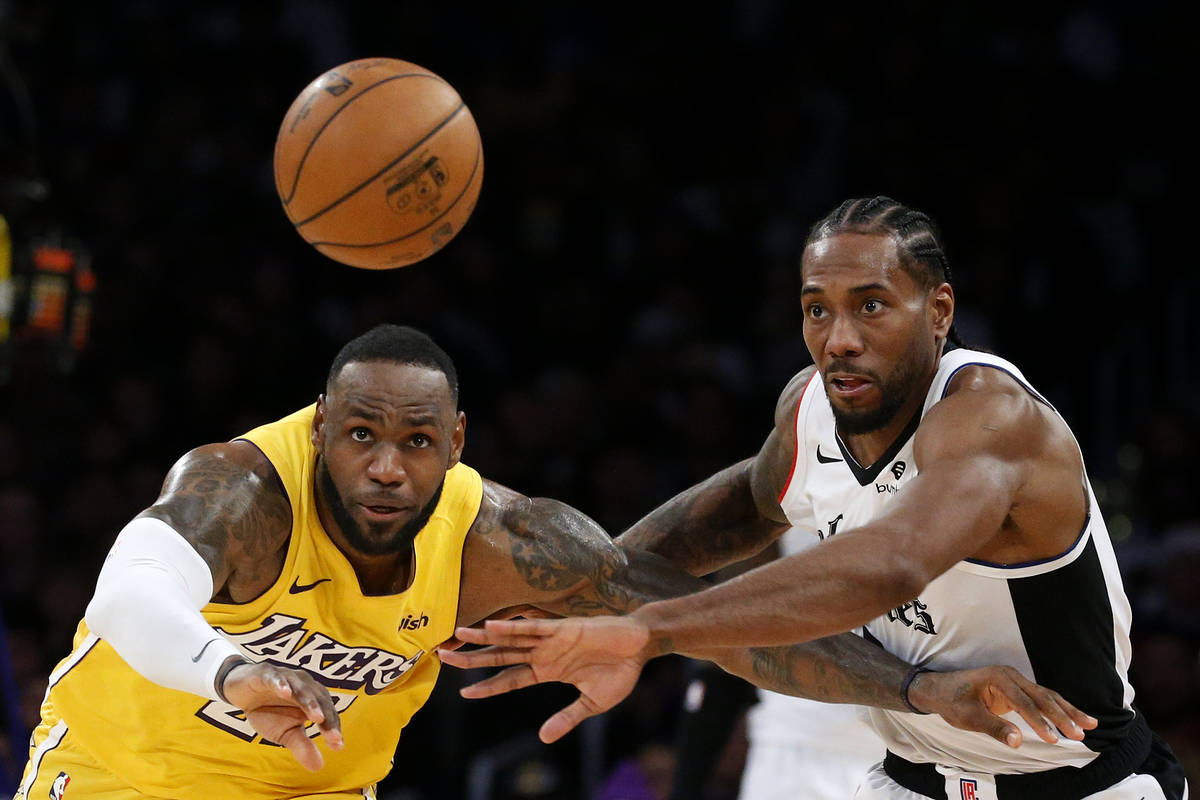 Los Angeles Lakers' LeBron James, left, and Los Angeles Clippers' Kawhi Leonard (2) chase the b ...