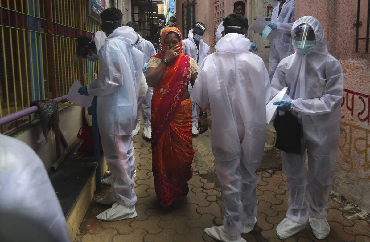 A woman covers her face as she walks past health workers arriving to administer a free medical ...