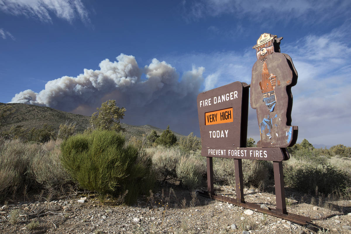 A Smokey the Bear sign indicates very high fire danger as the plume of smoke from the Mahogany ...