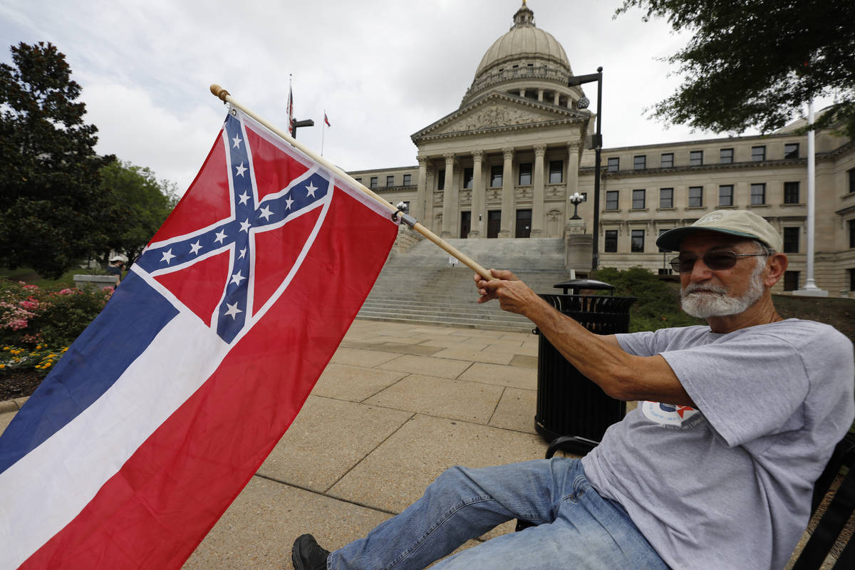 Larry Eubanks of Star waves the current Mississippi state flag as he sits before the front of t ...