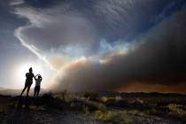 Amy Mojica, left, and her father Mauricio Mojica, take photos as the Mahogany Fire burns behind ...