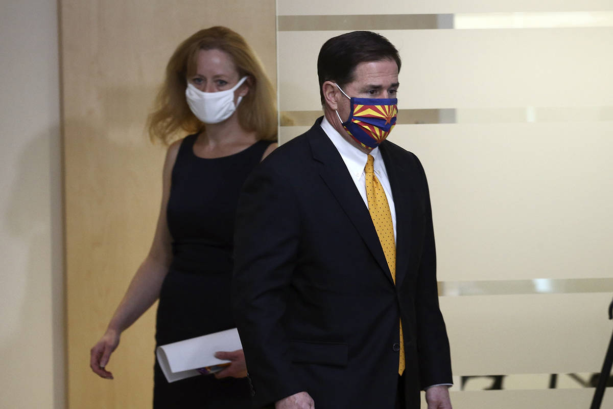 Arizona Republican Gov. Doug Ducey, right, and Arizona Department of Health Services Director D ...