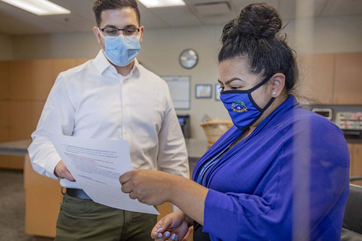 Front desk volunteer Nicholas Afshari, left, and social work program manager Lariza Soto go ove ...