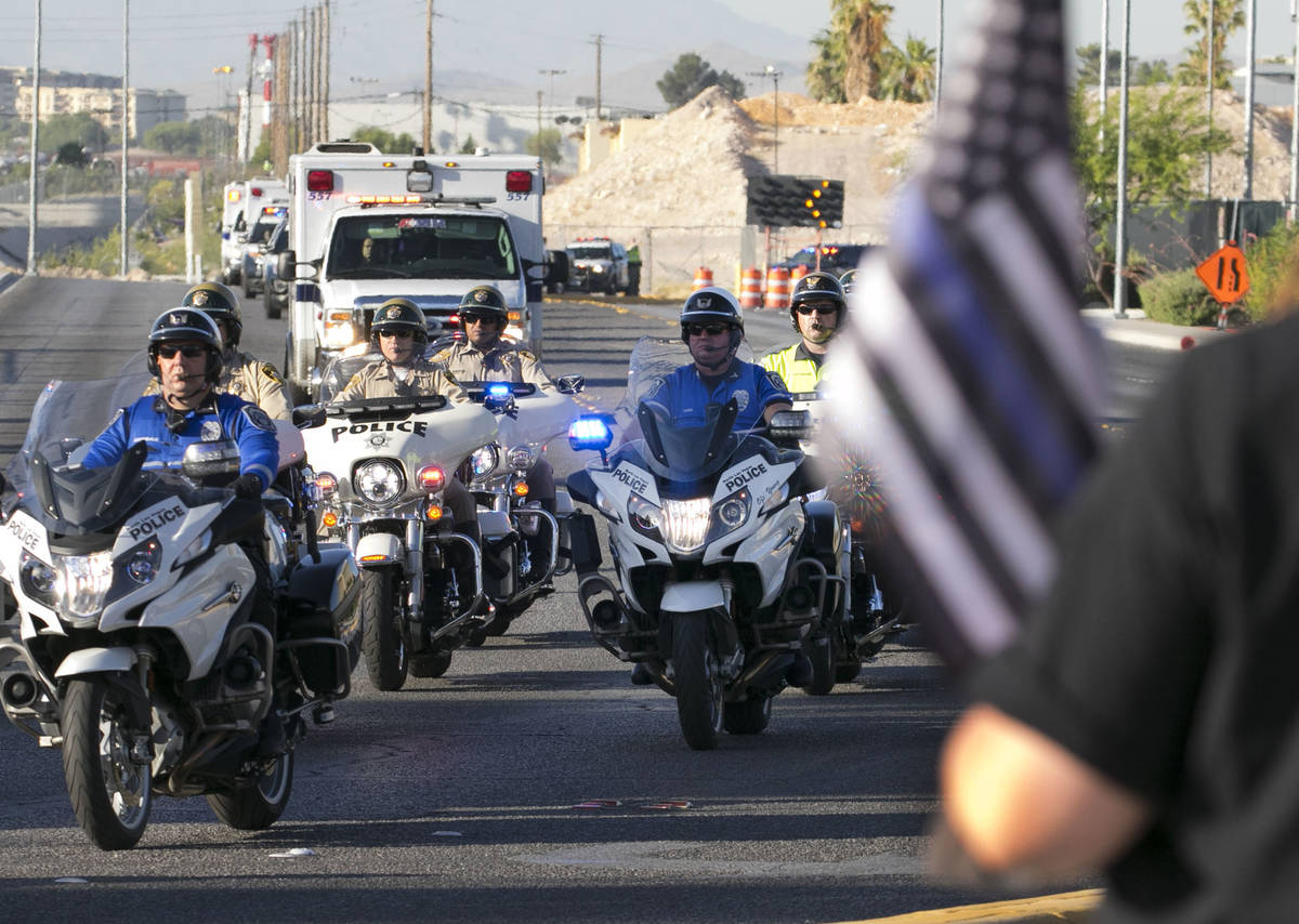 Cindy Novak, right, watches a procession as an ambulance carrying a wounded Las Vegas police of ...