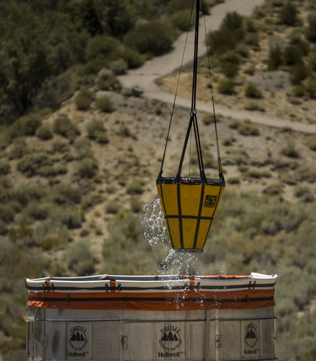 A water bucket is refilled for a helicopter above off of Kyle Canyon road for another drop over ...