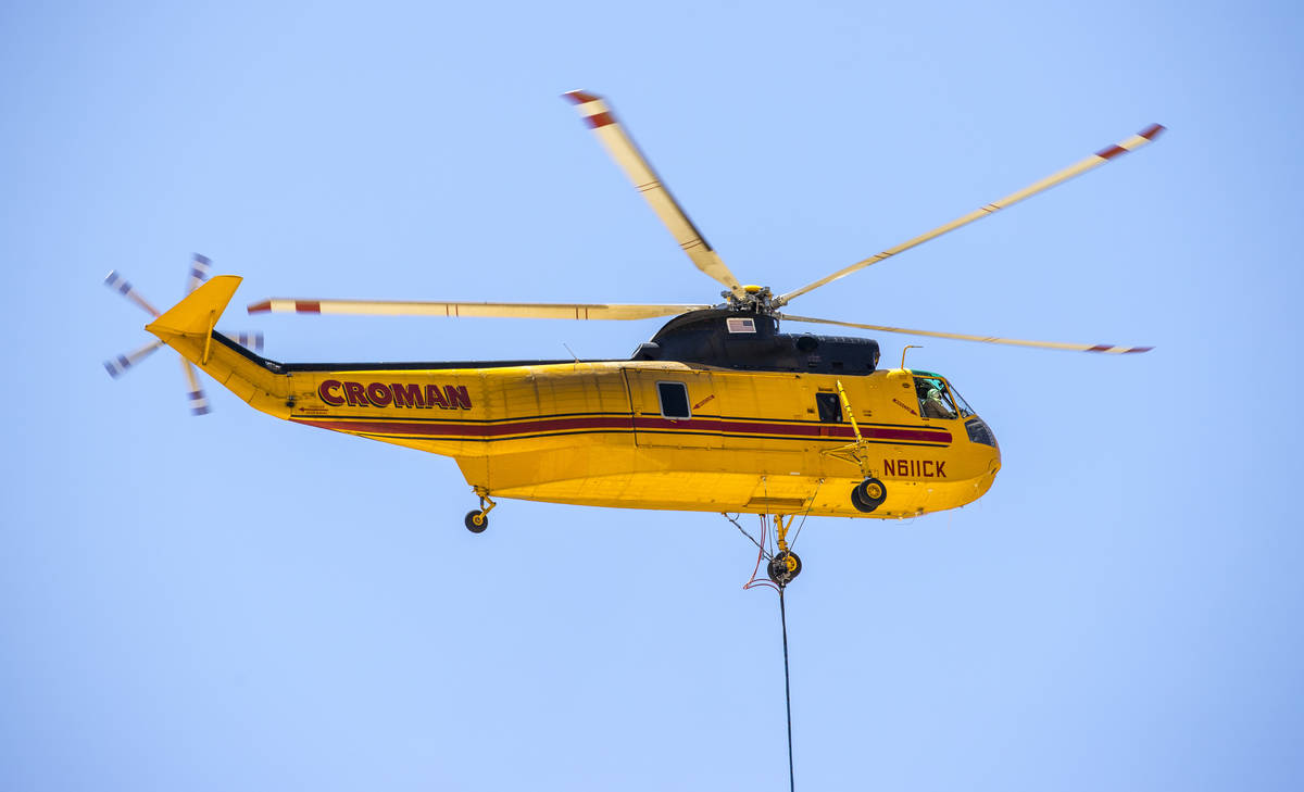 A helicopter with water bucket refills from a large water tank off Kyle Canyon Road for another ...