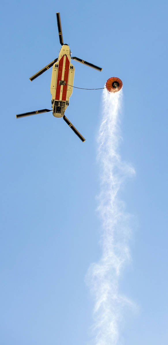 A helicopter with water bucket leaves the Lee Canyon Ski Resort for another drop over the Mahog ...