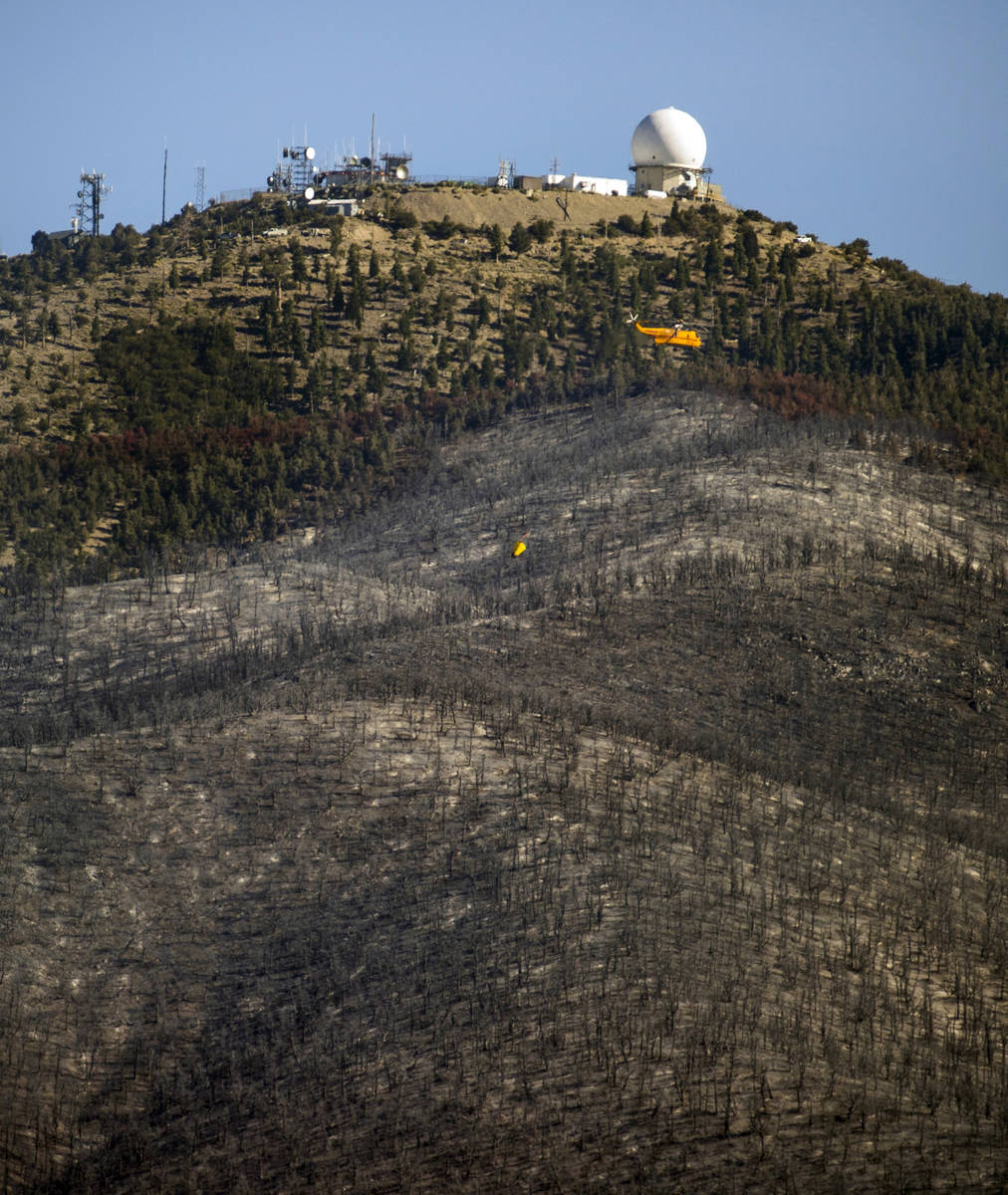 A helicopter with water bucket returns for another drop over the Mahogany Fire on Mount Charles ...