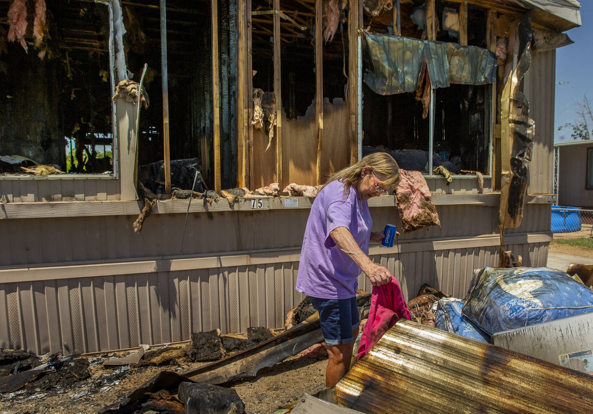 Claudia Arevala sorts through the remains of a fire in her home at the Town and Country Mobile ...