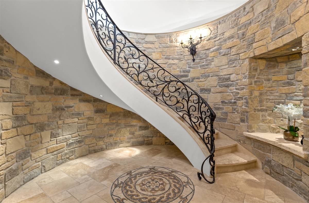 The grand staircase leads to the entertainment level downstairs. (Luxurious Real Estate)