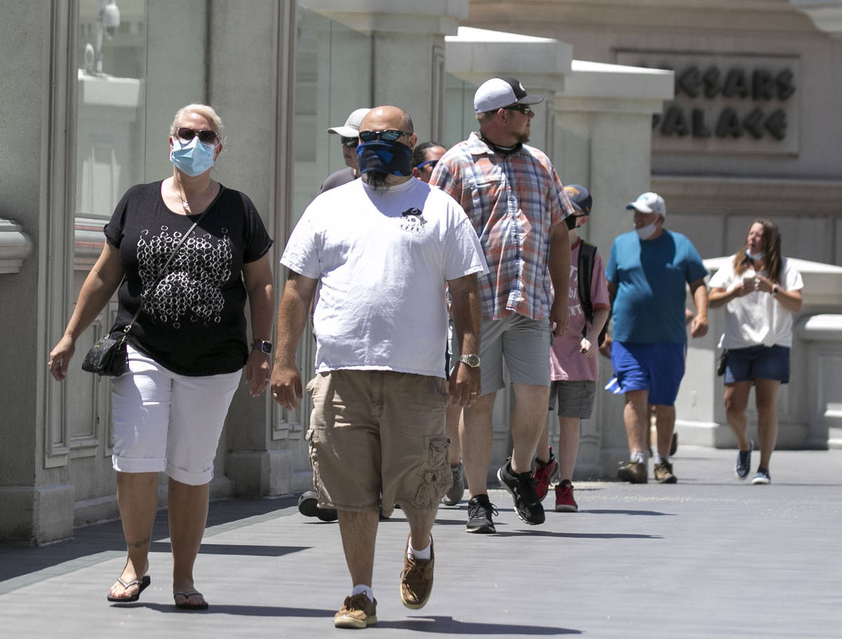 Tourists walk on the pedestrian bridge between Caesars Palace and The Flamingo on Friday, July ...