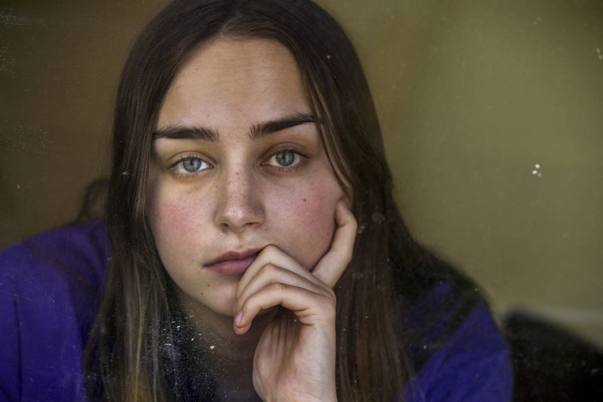 Kaydee Asher, 16, behind a window, is currently fighting the coronavirus and quarantined at hom ...