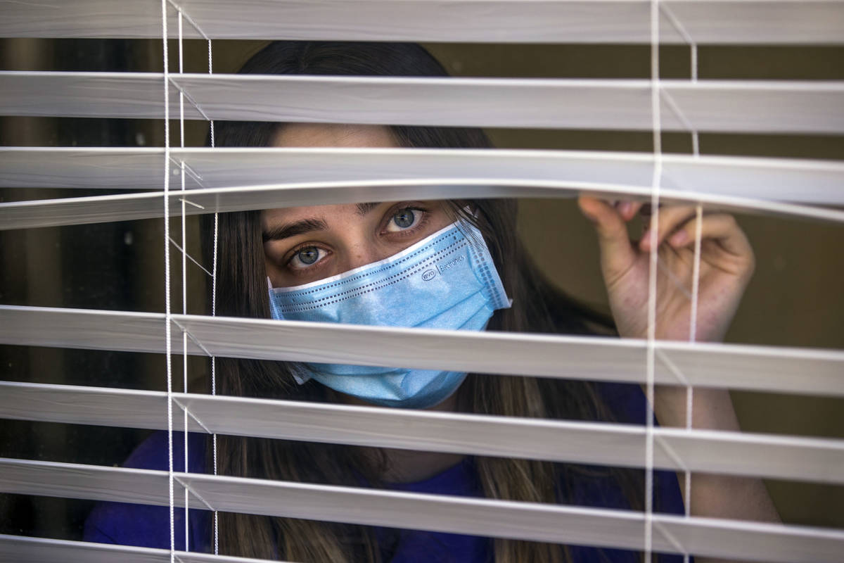 Kaydee Asher, 16, behind a window, is currently fighting the coronavirus and quarantined at hom ...