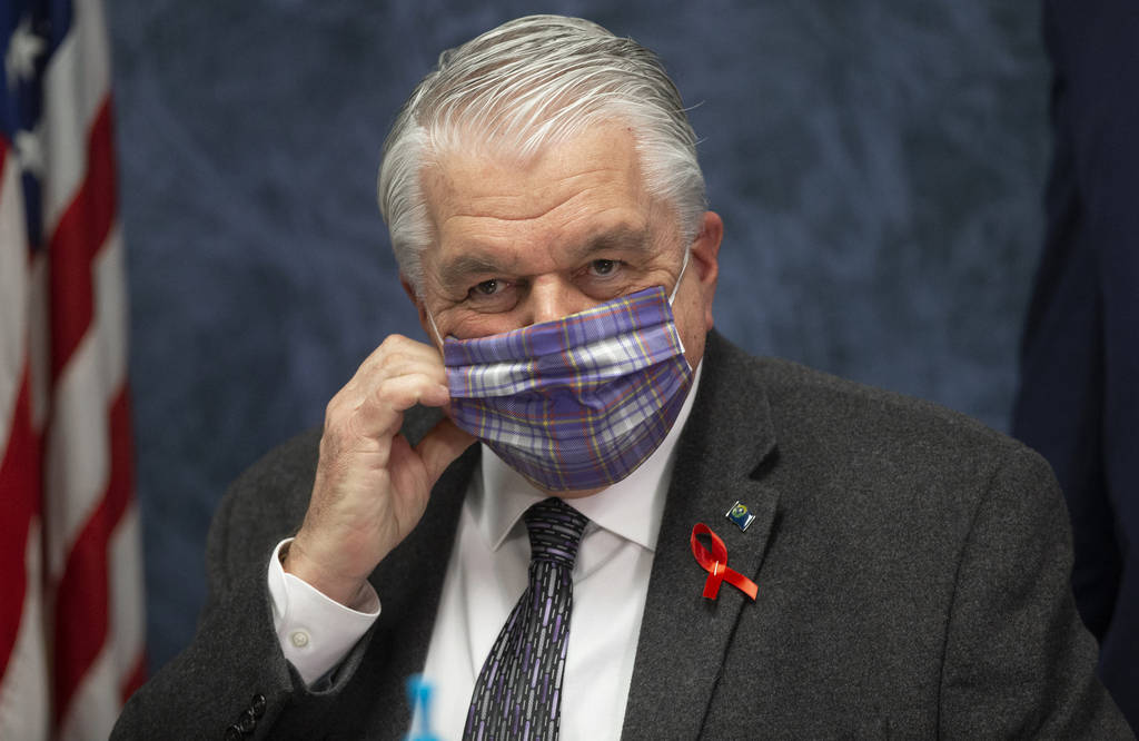 Gov. Steve Sisolak wears a protective mask before the start of a news conference to update Neva ...