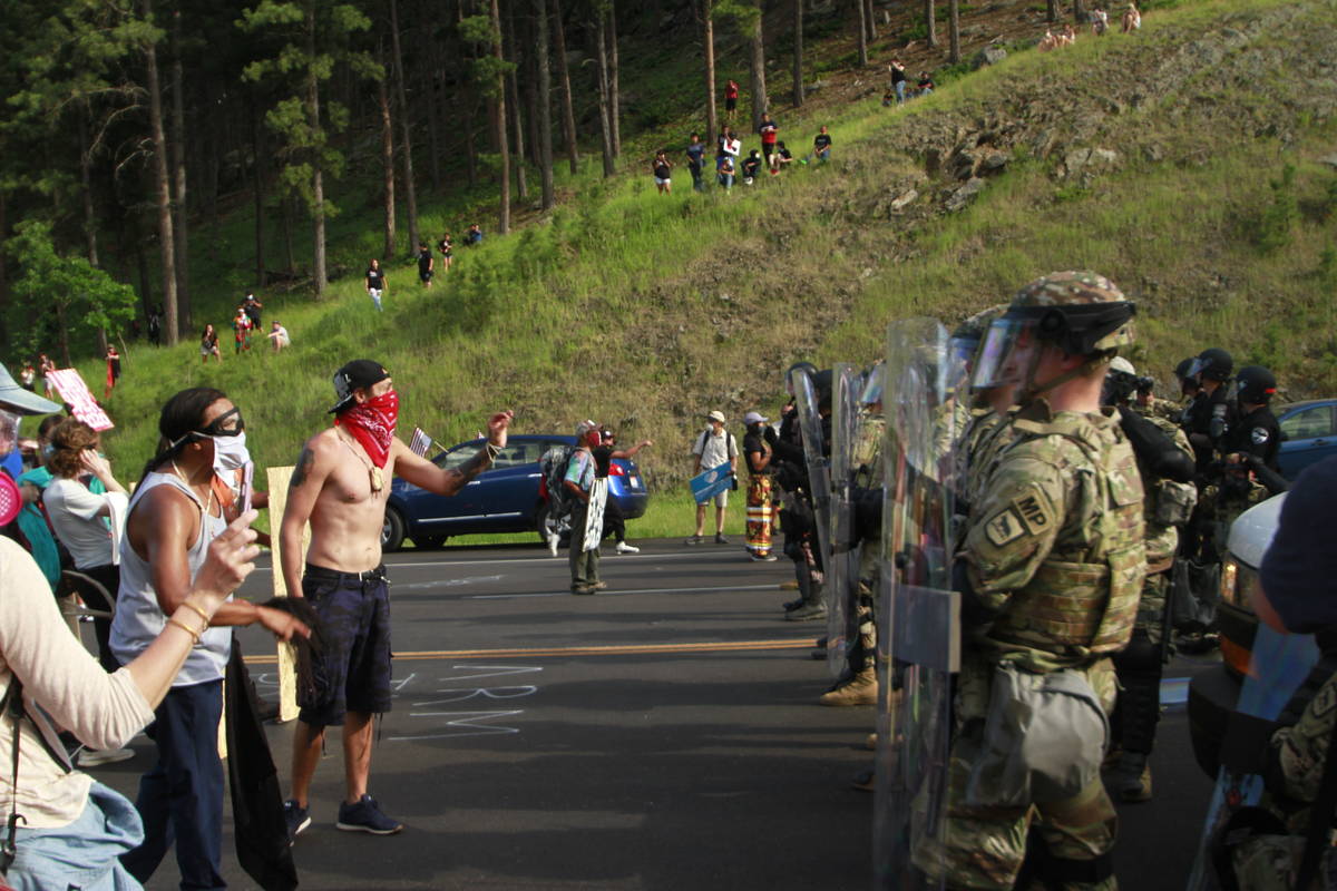 Protesters clash with a line of law enforcement officers in Keystone, S.D., on the road leading ...