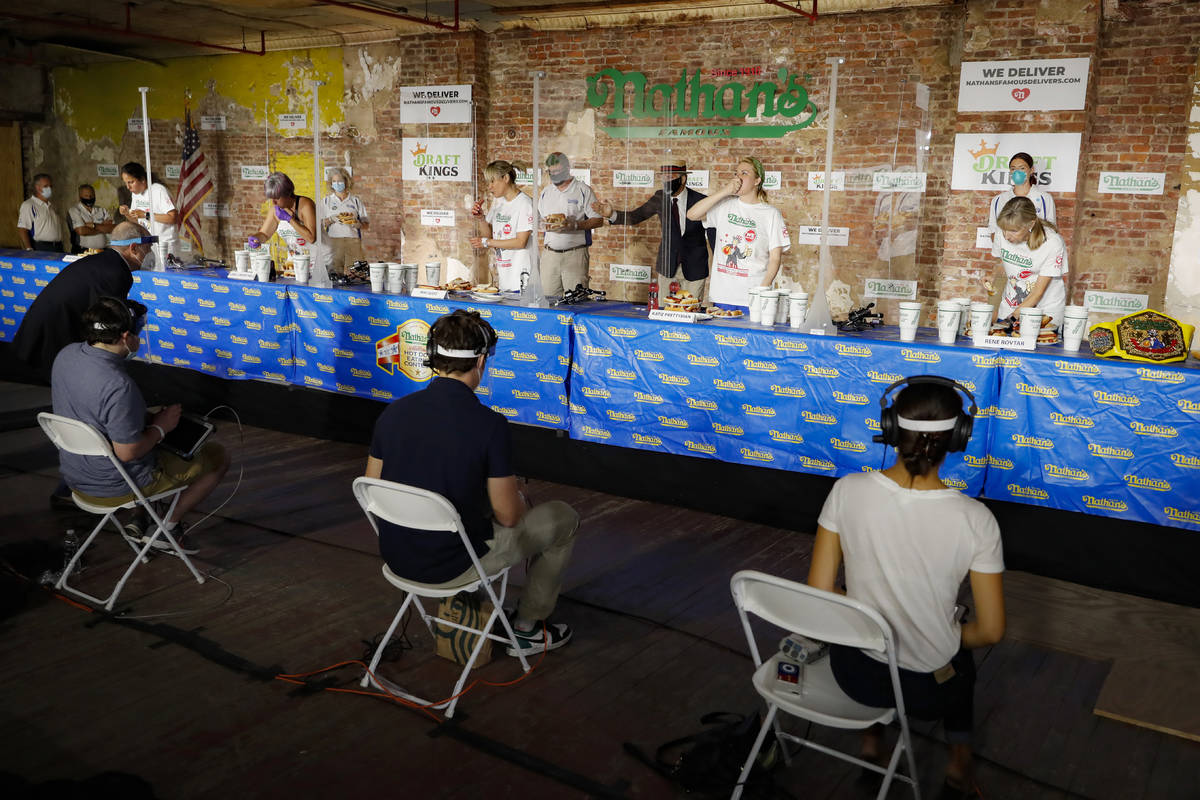 Competitors separated by translucent panels eat in the women's division of the Nathan's Famous ...