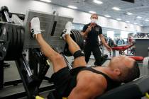 A trainer, top, at Mountainside Fitness, works with a client as the facility remains open even ...