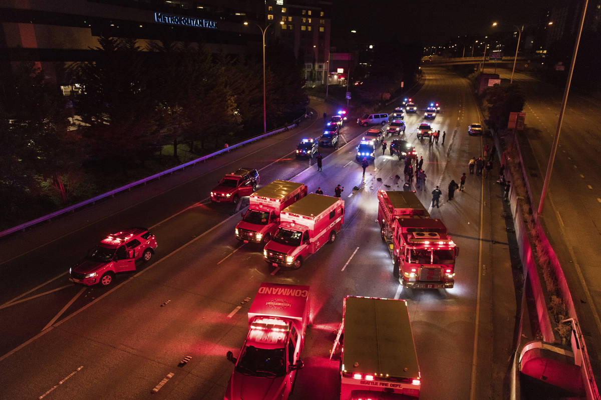 Emergency personnel work at the site where a driver sped through a protest-related closure on t ...