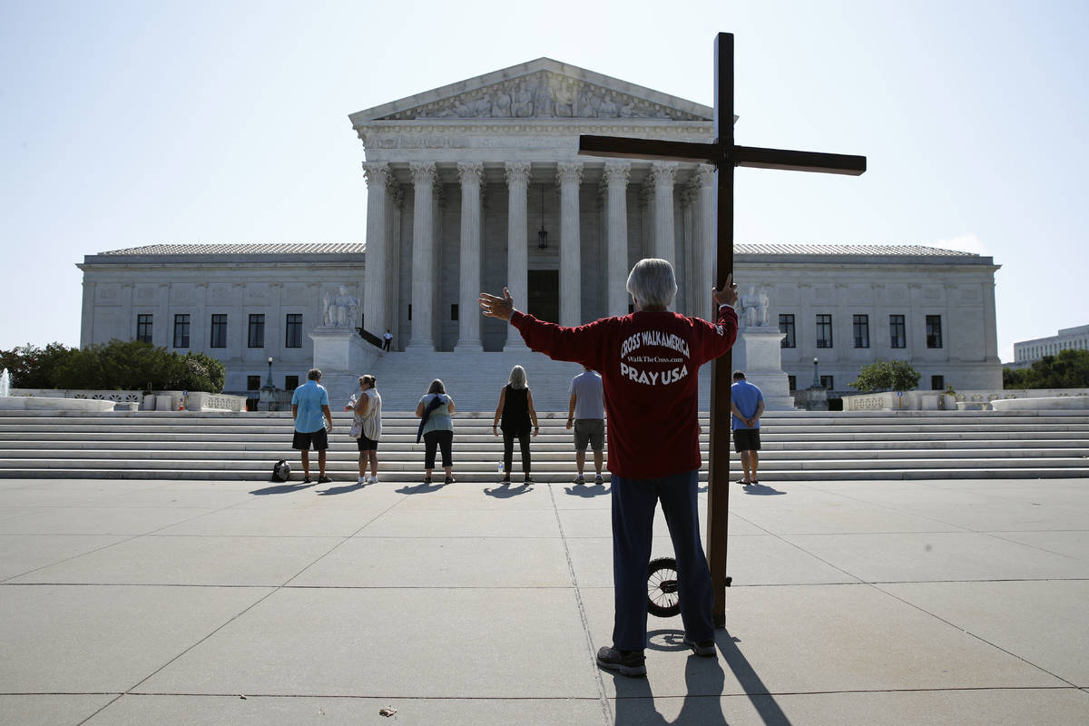Tom Alexander holds a cross as he prays prior to rulings outside the Supreme Court on Capitol H ...