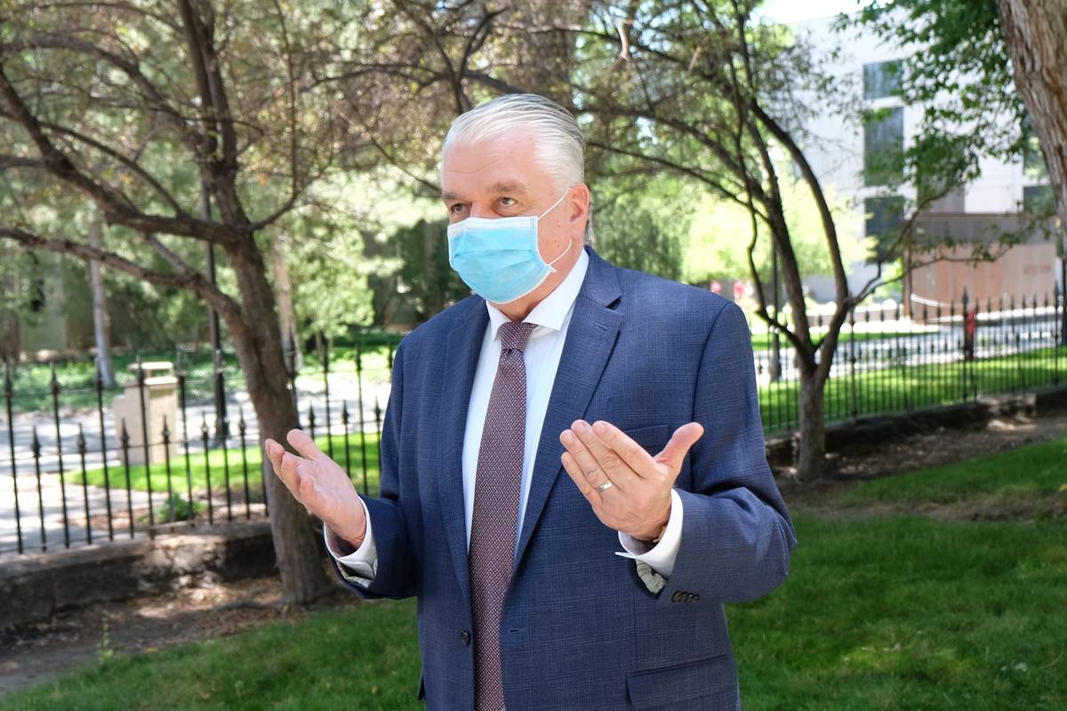 A masked Gov. Steve Sisolak speaks to reporters outside the Capitol Wednesday discussing spendi ...