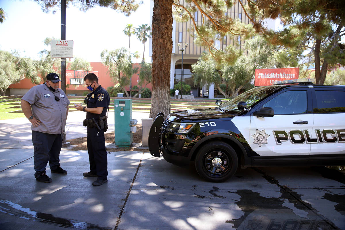 University Police Department officer Ryan Willman, right, speaks to a campus worker who flagged ...