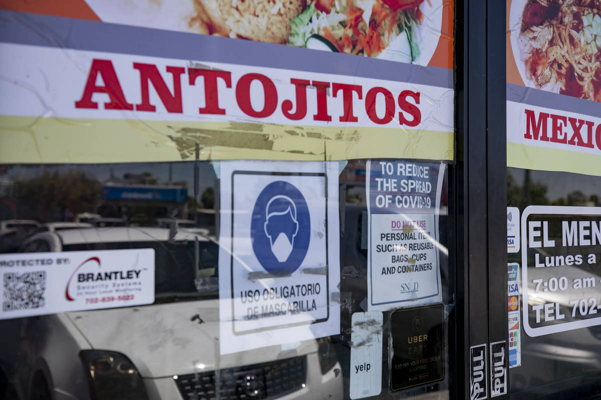 Signs requiring masks are posted on the doors of El Menudazo in North Las Vegas on Friday, July ...