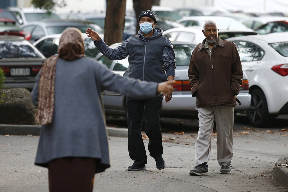 People gesture to each other as they walk outside public housing towers that are a hotspot for ...