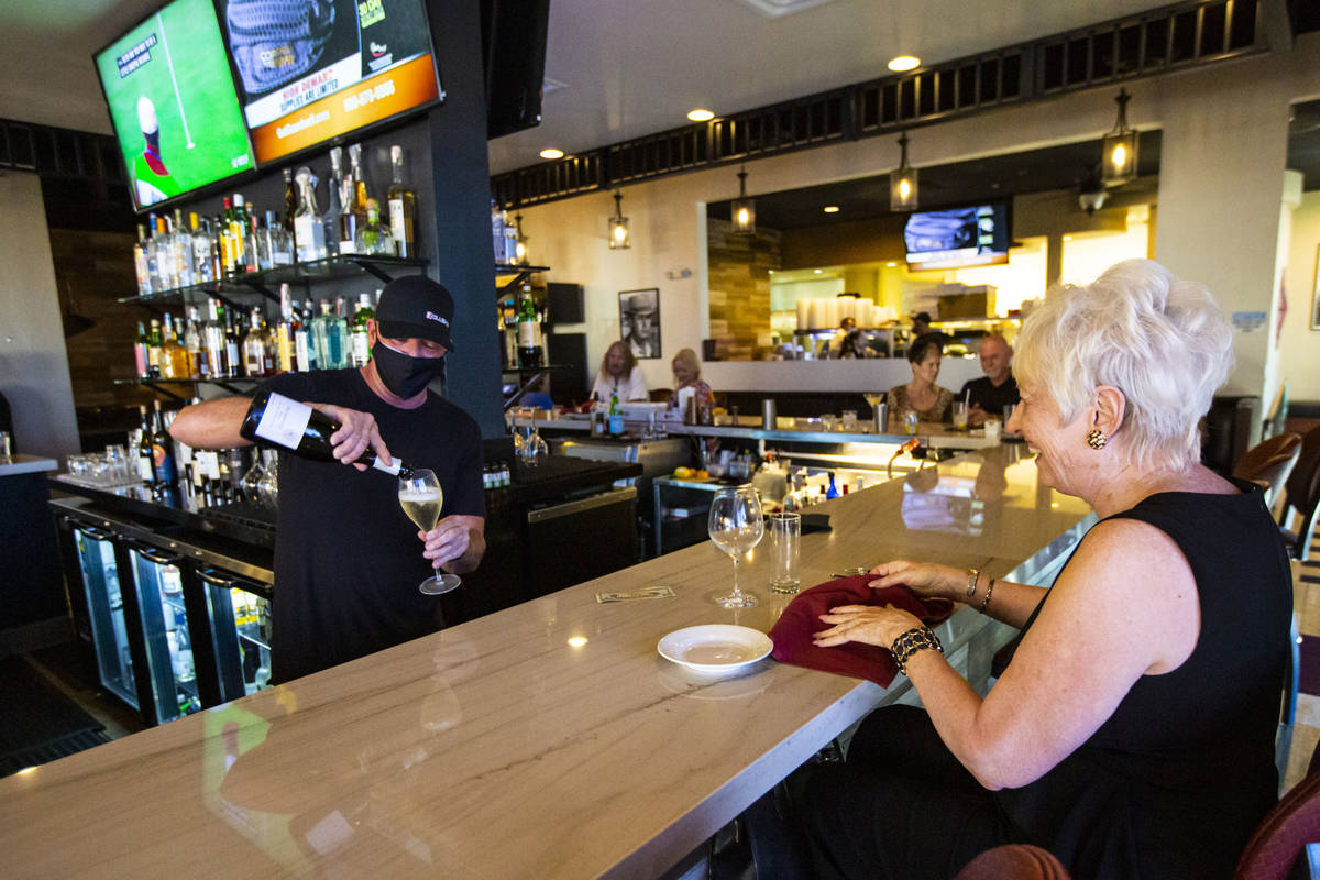 Bar manager David Cooper pours a drink for Dale Robins, of Las Vegas, during happy hour at Spag ...