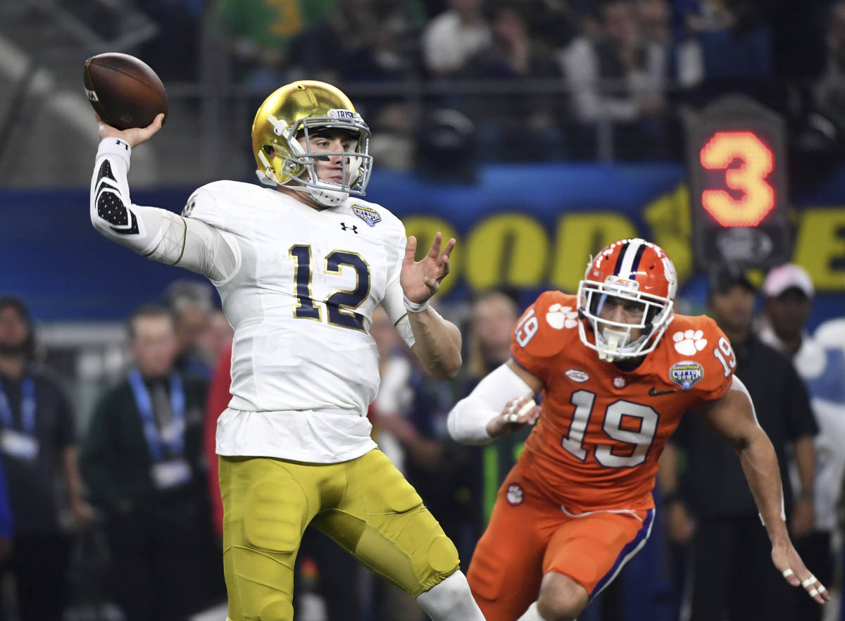 Notre Dame quarterback Ian Book (12) throws a pass under pressure from Clemson safety Tanner Mu ...
