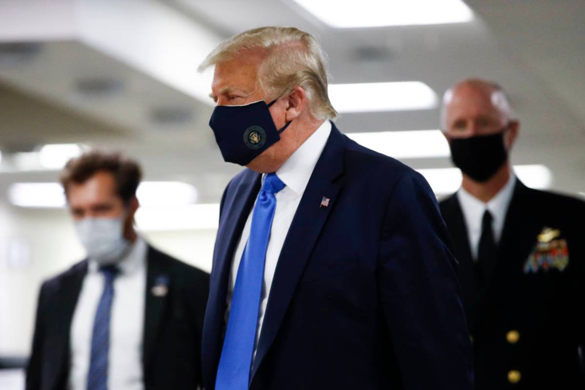 President Donald Trump wears a mask as he walks down the hallway during his visit to Walter Ree ...
