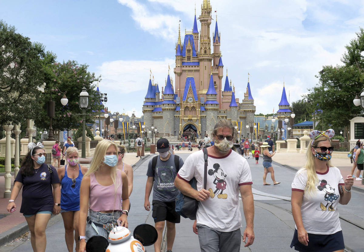 Guests wear masks as required to attend the official reopening day of the Magic Kingdom at Walt ...