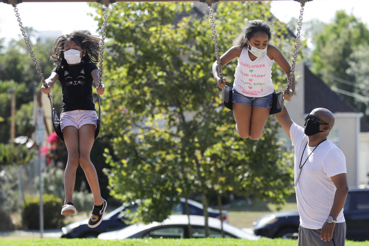 Afework Meshesha, right, pushes his daughter Yohanna while she rides a swing at a playground, S ...