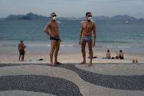 Jesus Costa and Antonio Ancon, right, stand on Copacabana beach amid the outbreak of the new co ...