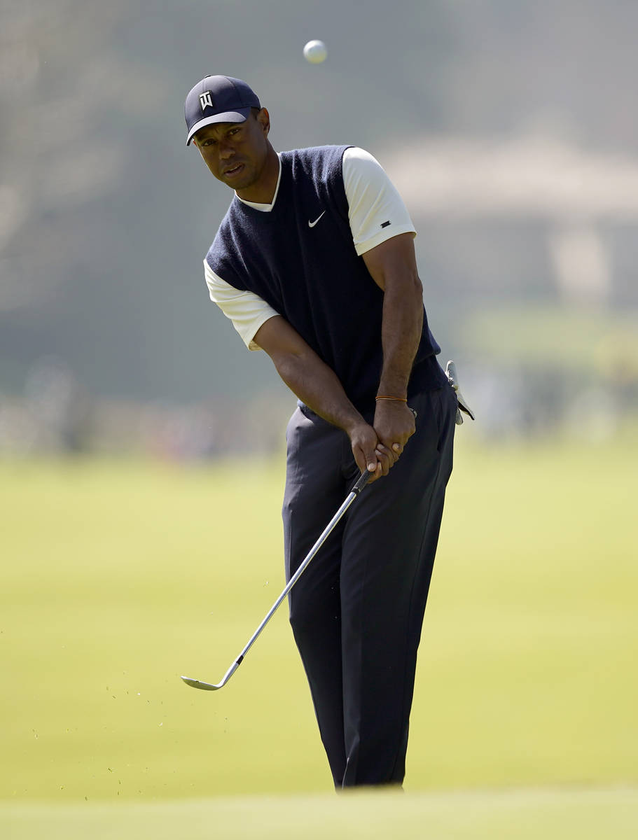 Tiger Woods chips onto the eighth green during the third round of the Genesis Invitational golf ...